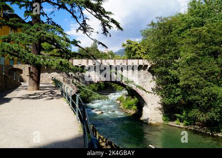 La pittoresca città mediterranea di Merano con un ponte in pietra ornato sul fiume verde smeraldo Passero (Italia, Trentino-Alto Adige, Alto Adige) Foto Stock