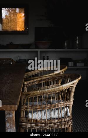 Due sedie in vimini e un tavolo all'interno con decorazioni rurali Foto Stock