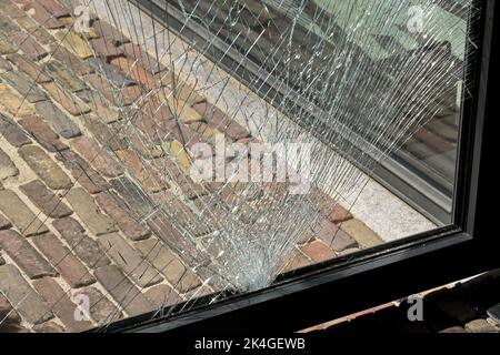 Vista ravvicinata delle crepe in un vetro temprato di una porta dopo essere stato colpito da un oggetto. Nessuna gente. Foto Stock