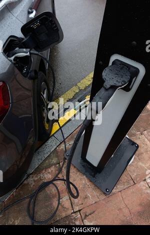 Vista ravvicinata del connettore di una stazione di carica elettrica con un concetto di auto collegata riducendo le emissioni di CO2 attraverso l'energia alternativa come sostentamento Foto Stock