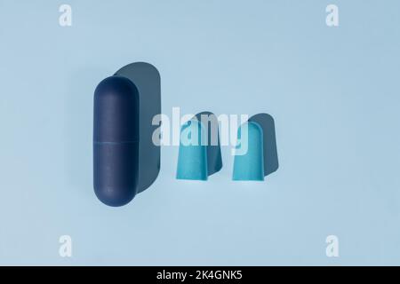 Inserti auricolari blu in schiuma per un sonno confortevole su sfondo blu. Concetto di insonnia, giacitura Foto Stock