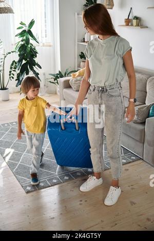 Madre e bambino con una valigia sono costretti a lasciare la loro casa. Trasferimento di famiglia, volo dal paese, frontiere chiuse Foto Stock
