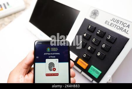 Brasile. 01st Ott 2022. In questa illustrazione, l'app e-Title visualizzata sullo schermo di uno smartphone con un urno elettronico sullo sfondo. (Foto di Rafael Henrique/SOPA Images/Sipa USA) Credit: Sipa USA/Alamy Live News Foto Stock