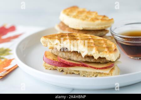 Sandwich con waffle, mela e salsiccia servito con sciroppo d'acero per l'immersione. Foto Stock