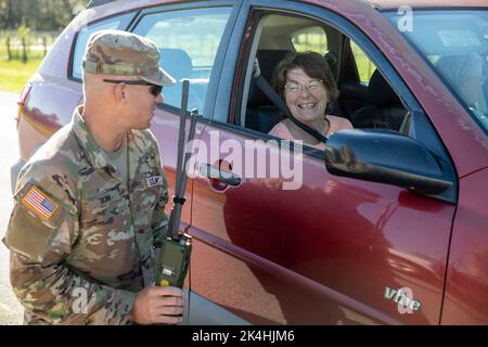 US Army PFC. Kenneth Bonn, ingegnere di combattimento con la 753rd Engineering Brigade, dirige Mary Roler attraverso la chiusura delle strade durante gli sforzi di soccorso dell'uragano Ian a Sarasota, Fla., 30 settembre 2022. I beni dell'esercito e della Guardia aerea sono stati attivati per servire la comunità durante il loro tempo di bisogno. Le squadre di soccorso, i servizi di bonifica stradale e la distribuzione delle risorse erano alcuni dei compiti che le truppe hanno svolto in tutto lo stato. Oltre 6.000 membri del servizio sono stati attivati in risposta al disastro naturale, insieme al sostegno militare e civile proveniente da luoghi non statali. (STATI UNITI Esercito foto di Foto Stock