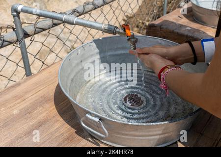 Mani aperte per bere acqua di rubinetto. Versare una bevanda fresca e sana. Buona abitudine. La scelta giusta. Il bambino lava la mano sotto il rubinetto nel giardino. Foto Stock