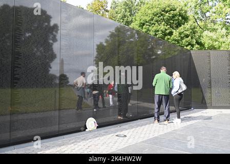 I visitatori e il Washington Monument si riflettono nel granito nero del Vietnam Memorial Wall a Washington, DC. Foto Stock