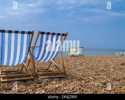 Brighton Beach e le caratteristiche sedie a sdraio a strisce in blu o rosso e bianco. Foto Stock