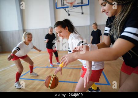 Donne multigenerazionali che giocano a basket in palestra. Foto Stock