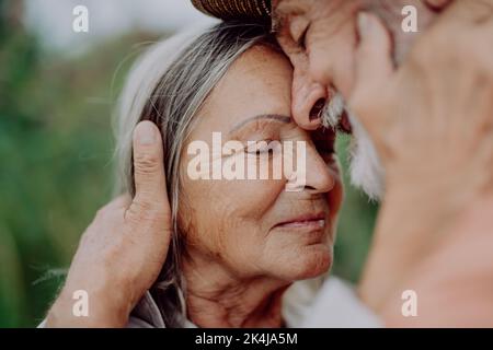 Ritratto di coppia anziana innamorata, in piedi all'aperto in natura. Foto Stock