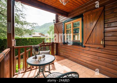 Portico di eco casa casolare in legno con tavolo e sedie. Weekend accogliente in campagna. Vacanza estiva all'aria aperta, concetto di relax. Foto Stock