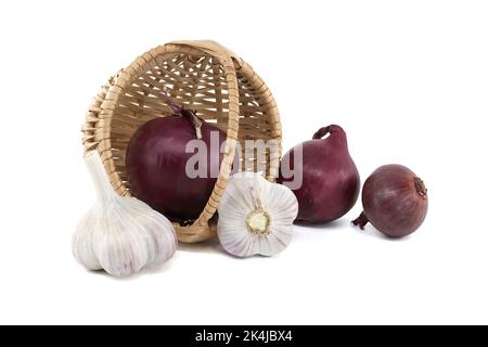 Cipolle rosse e bulbi d'aglio cadono dal cesto di vimini su sfondo bianco Foto Stock