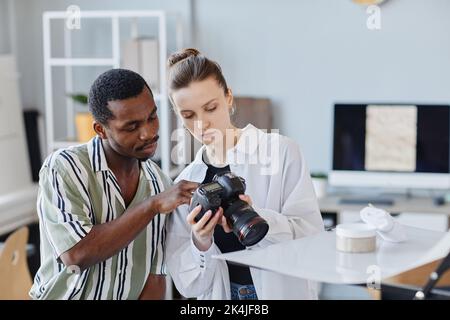 Ritratto di due fotografi che scattano immagini di prodotti con una fotocamera professionale in studio Foto Stock