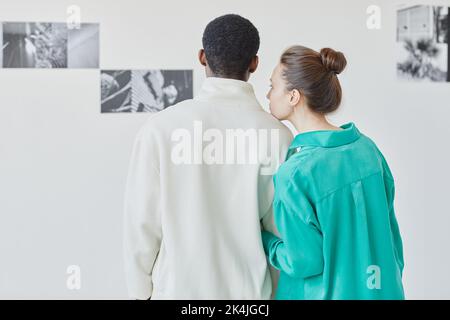 Vista posteriore minima di una giovane coppia che guarda la galleria fotografica nel museo insieme, spazio copia Foto Stock