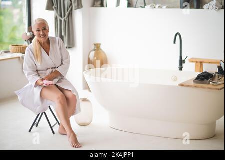 Donna a piedi nudi in accappatoio preparazione per il drenaggio linfatico auto-massaggio Foto Stock