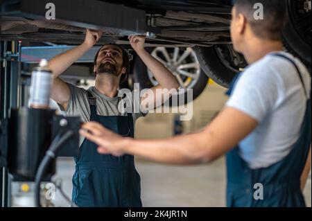 Il personale del servizio di riparazione automatica ispeziona il veicolo del cliente Foto Stock