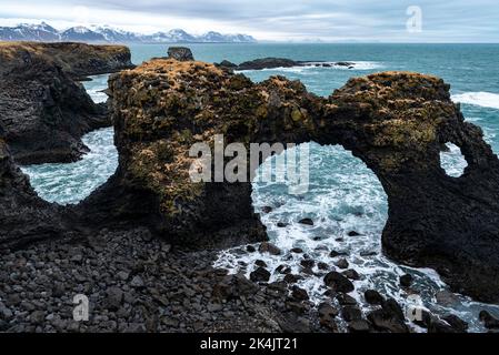 Primo piano dell'arco di roccia di Gatklettur nel tardo inverno, presso le scogliere di basalto nero di Arnarstapi sulla costa meridionale della penisola di Snæfellsnes, Islanda Foto Stock