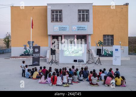 Batman, Turchia. 02nd Ott 2022. I bambini guardano attentamente il film animato nella loro lingua madre nel giardino della scuola. Batman Culture and Art Association organizza un evento cinematografico che introduce il cinema ai bambini che non hanno ancora conosciuto il cinema a Batman e nei villaggi dei suoi quartieri. L'associazione porta il film d'animazione di Hayao Miyazaki 'My Neighbor Totoro' nei villaggi come un doppiaggio curdo. Credit: SOPA Images Limited/Alamy Live News Foto Stock