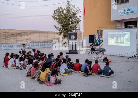 Batman, Turchia. 02nd Ott 2022. I bambini guardano attentamente il film animato nella loro lingua madre nel giardino della scuola. Batman Culture and Art Association organizza un evento cinematografico che introduce il cinema ai bambini che non hanno ancora conosciuto il cinema a Batman e nei villaggi dei suoi quartieri. L'associazione porta il film d'animazione di Hayao Miyazaki 'My Neighbor Totoro' nei villaggi come un doppiaggio curdo. Credit: SOPA Images Limited/Alamy Live News Foto Stock