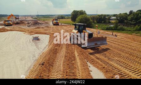 Lavori attivi in cantiere. Un camion dumper con terra in un cassone, trasportandolo. Macchine da costruzione pesanti. Varsavia, Polonia. Vista dall'alto dell'antenna. Foto di alta qualità Foto Stock