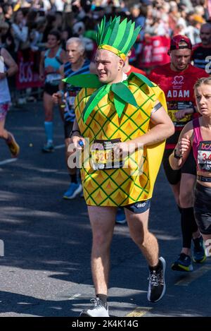 Simon Howard corre nella TCS London Marathon 2022, sulla Tower Hill Road, City of London, Regno Unito, indossando un costume di ananas Foto Stock