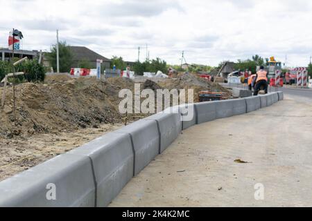 Regione di Cimislia, Moldavia - 20, settembre, 2022: Costruzione di un incrocio stradale sulla strada statale E584/M3. Lavoratori che spostano il marciapiede della strada, montando blocchi nel Foto Stock