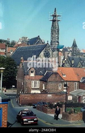 1987STEEPLEJACKS - Una vista da Spring Hill e Princess Place dei lavoratori che sostituiscono un vecchio campanile instabile con una sostituzione in fibra di vetro più breve sulla Chiesa cattolica ai piedi di Brunswick Street, nel Whitby North Yorkshire. . La trama a destra dell'uomo sulla destra era un tempo il sito della vecchia stazione di polizia della città. Foto Stock