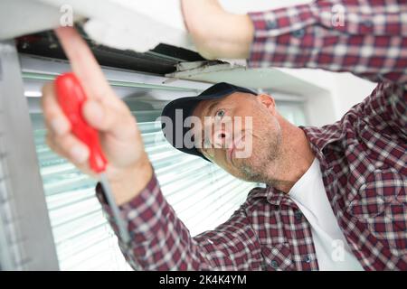 un uomo sta installando i ciechi Foto Stock