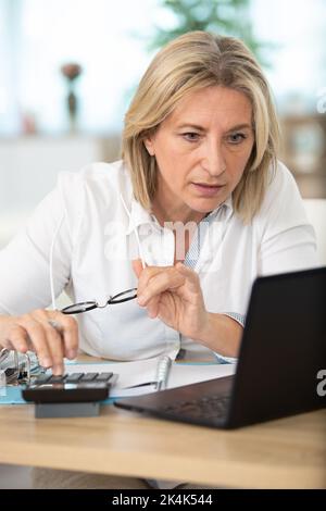 impiegati senior che guardano il laptop e utilizzano la calcolatrice Foto Stock