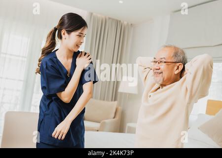 fisioterapista femminile che aiuta l'uomo anziano ad esercitare, aiutando il paziente anziano di sesso maschile a letto al mattino Foto Stock