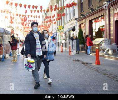 Londra, Inghilterra, Regno Unito. Giovane coppia cinese a Chinatown con maschere facciali durante la pandemia COVID, marzo 2022 Foto Stock