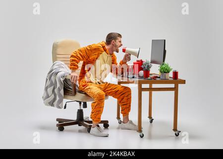 Giovane uomo in costume incredibile grida al megafono di casa. Minimalismo colorato. Buon Natale, Capodanno Foto Stock