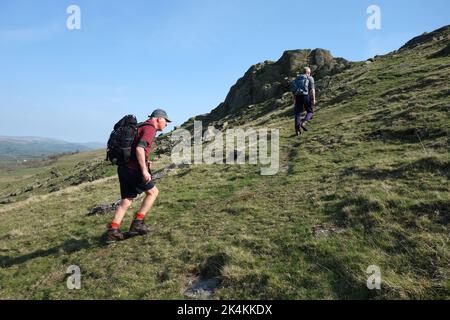 Due uomini camminano fino a Devil's Crag sulla strada per il Mountain Castle Knott tra lo Yorkshire Dales & Lakes National Park, Inghilterra, Regno Unito. Foto Stock