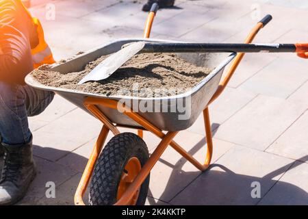 carriola da costruzione con sabbia e pala Foto Stock