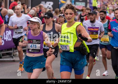 Corridore ipovedente con guida che corre nella maratona di Londra 2022 del TCS, sulla strada di avvicinamento del ponte della torre, Regno Unito. Lisa Thompson & guida Pappas Foto Stock