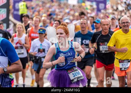 Rebecca Kealy correndo nel TCS London Marathon 2022, sulla strada di avvicinamento Tower Bridge, City of London, UK, con la massa di corridori che seguono Foto Stock