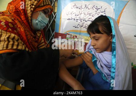 Operatore sanitario che somministra la vaccinazione contro l'epidemia di anti-tifo agli studenti delle scuole durante la campagna di immunizzazione anti-tifo, tenutasi presso il Governo Girls High School Nothia a Peshawar lunedì 03 ottobre 2022. Foto Stock