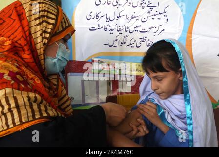 Operatore sanitario che somministra la vaccinazione contro l'epidemia di anti-tifo agli studenti delle scuole durante la campagna di immunizzazione anti-tifo, tenutasi presso il Governo Girls High School Nothia a Peshawar lunedì 03 ottobre 2022. Foto Stock