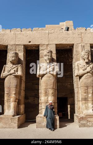 Luxor, Egitto - 17 gennaio 2019: Un egiziano in vestito nazionale si trova sullo sfondo di antiche sculture e colonne egiziane nel sacro Ka Foto Stock