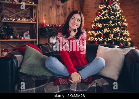 Foto del corpo pieno di adorabile signora seduta divano dito tocco mento immaginare di nuovo anno magico casa al coperto Foto Stock