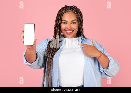 Sorridente Female Africana americana che mostra lo schermo del cellulare, Studio Shot Foto Stock