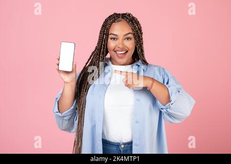 African American Lady Holding smartphone che indica lo schermo, sfondo rosa Foto Stock