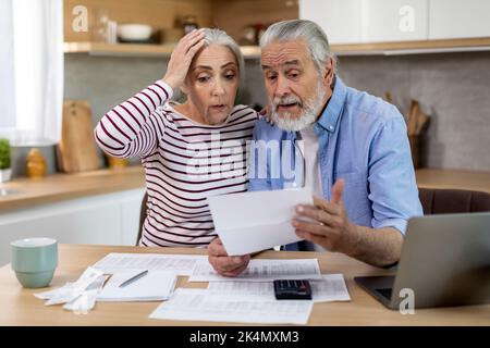 Crisi di bilancio. Scioccato sposi anziani che controllano i documenti finanziari a casa Foto Stock