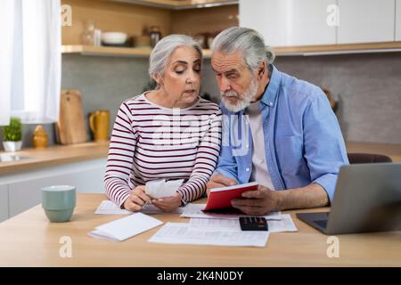 Concetto economico. Coppia senior che gestisce le finanze, contando le spese familiari in cucina Foto Stock