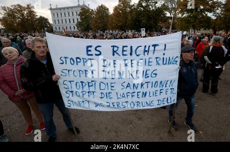 Schwerin, Germania. 03rd Ott 2022. I partecipanti ad una manifestazione contro la politica energetica si riuniscono davanti al castello di Schwerin, una bandiera recita 'basta! Fermare il governo fermare la guerra fermare le sanzioni fermare la fornitura di armi. Fermare la distruzione di Deu`s'. Secondo le autorità di assemblaggio, in diverse città sono previste manifestazioni contro il forte aumento dei prezzi dell'elettricità e del gas e le conseguenze dell'inflazione. Credit: Bernd Wüstneck/dpa/Alamy Live News Foto Stock