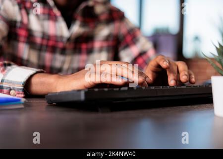 Freelance maschio che naviga in internet sul computer, scrivendo un rapporto online alla scrivania di casa e inviando e-mail. Lavorare in remoto con un'azienda freelance, utilizzando il pc per eseguire i file di documentazione. Primo piano. Foto Stock