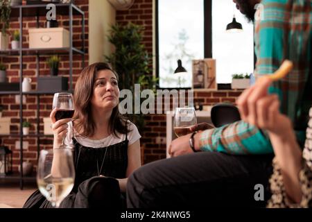 Ansioso, preoccupato, stressato, donna caucasica in appartamento, residenza compagni di riunione. Culturalmente diversi, etnie diverse, nazionalità amici conversazione, discussione nel soggiorno casa. Foto Stock