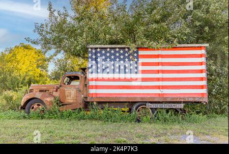 Vecchio pickup schivata con una grande bandiera americana Foto Stock