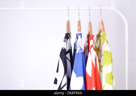 Camicie femminili multicolore con strisce su grucce su sfondo bianco. Foto Stock