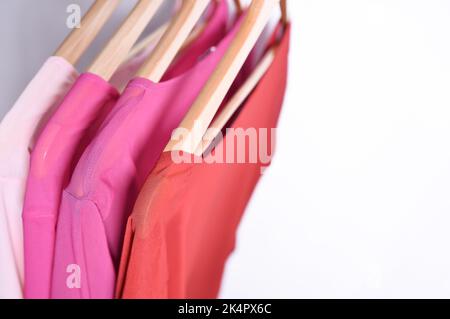 Camicie femminili multicolore con strisce su grucce su sfondo bianco. Foto Stock